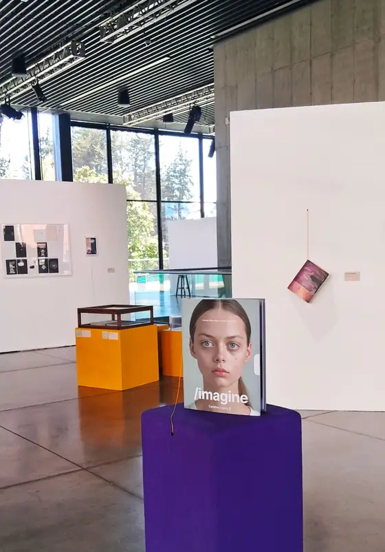 The /imagine book standing on a purple plinth in a bright exhibition hall.