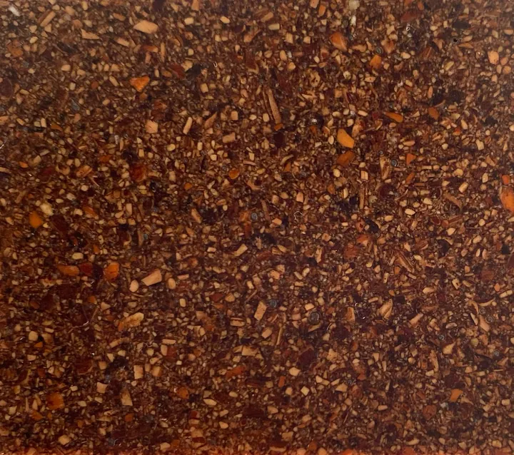Close-up of Nutty: dark crushed organic particles locked into bio-resin.