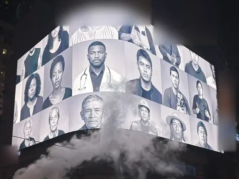 At night the same corner screen shows the portraits in black and white; steam rises from the street.